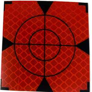 Small square target with concentric circles and a crosshair on an orange background, placed on a white surface.